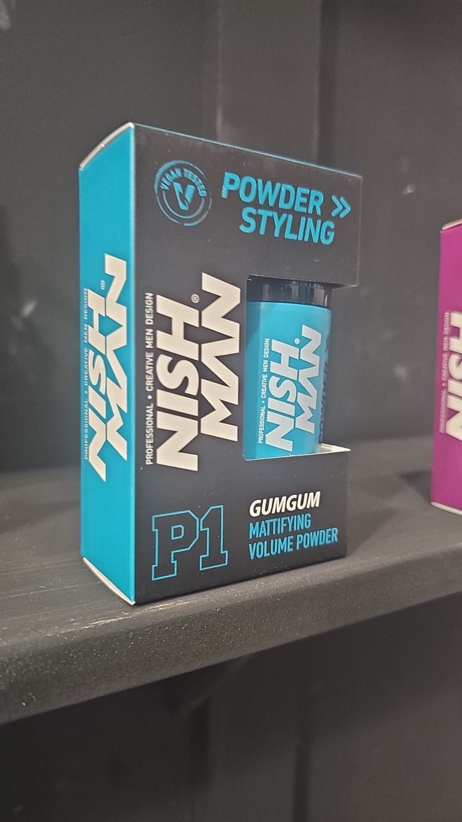 Nish Man styling product packaging on a dark surface